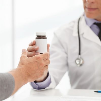 Health Care practitioner places pill bottle in hand of patient